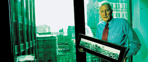 Pete Petersen holds a photo of the aftermath of The Great Baltimore Fire in his office, which looks out onto where the fire happened.
